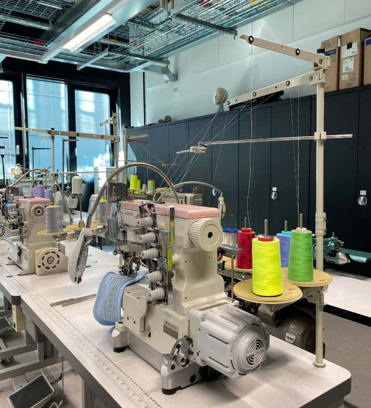 Industrial sewing machines and colourful thread in a garment factory – red flags when choosing a clothing manufacturer