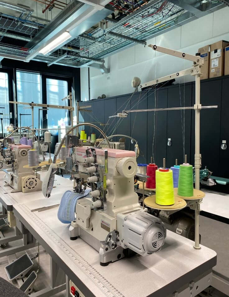 Industrial sewing machines and colourful thread in a garment factory – red flags when choosing a clothing manufacturer