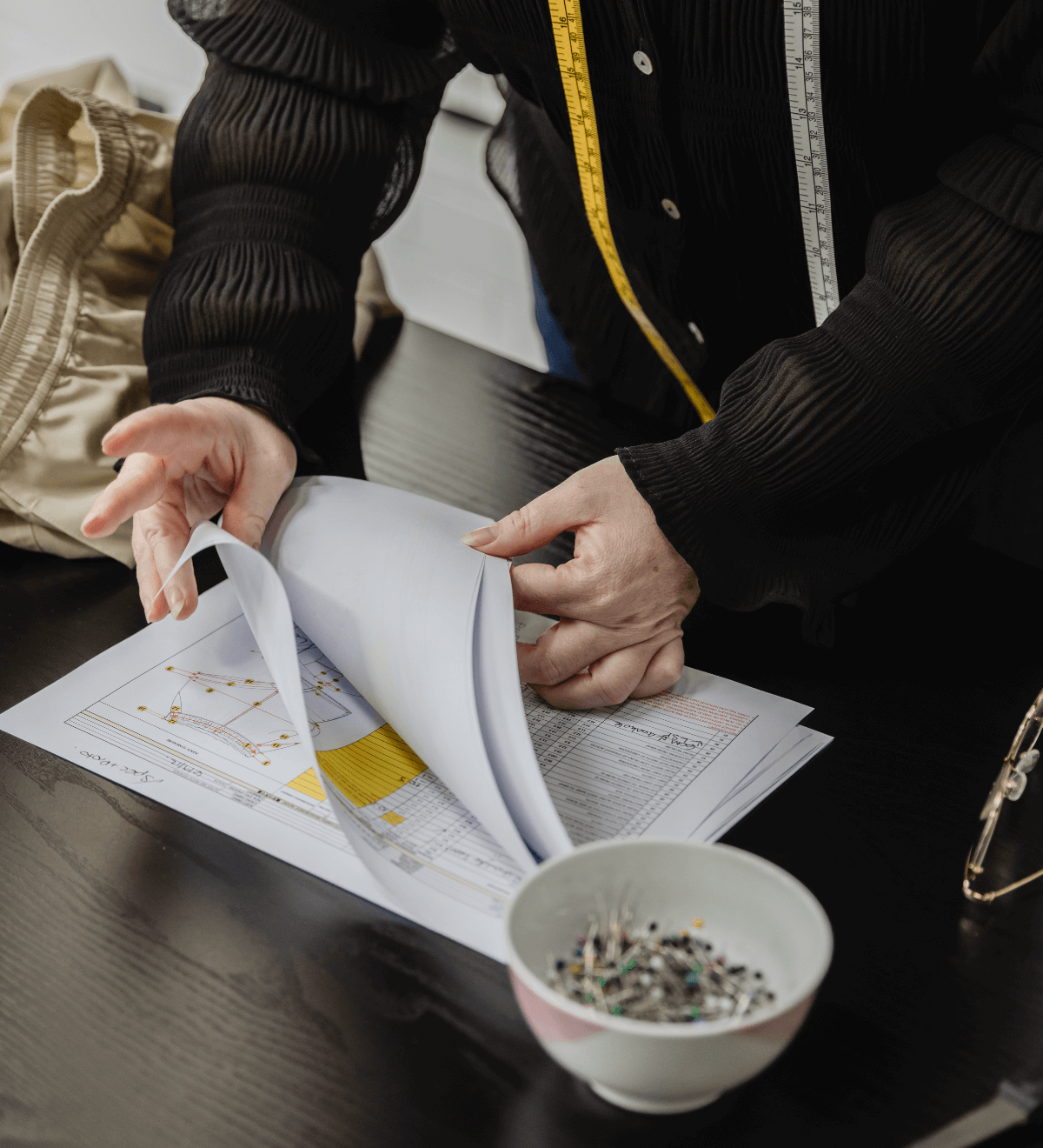Fashion Designer measuring a sample garment and recording the findings into the tech pack.
