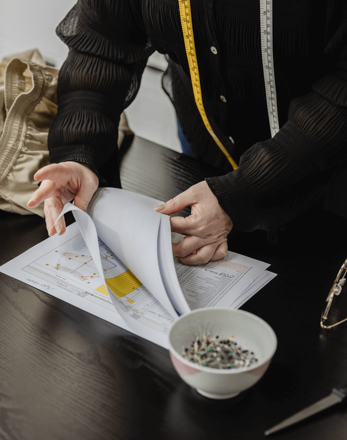 Fashion Designer measuring a sample garment and recording the findings into the tech pack.