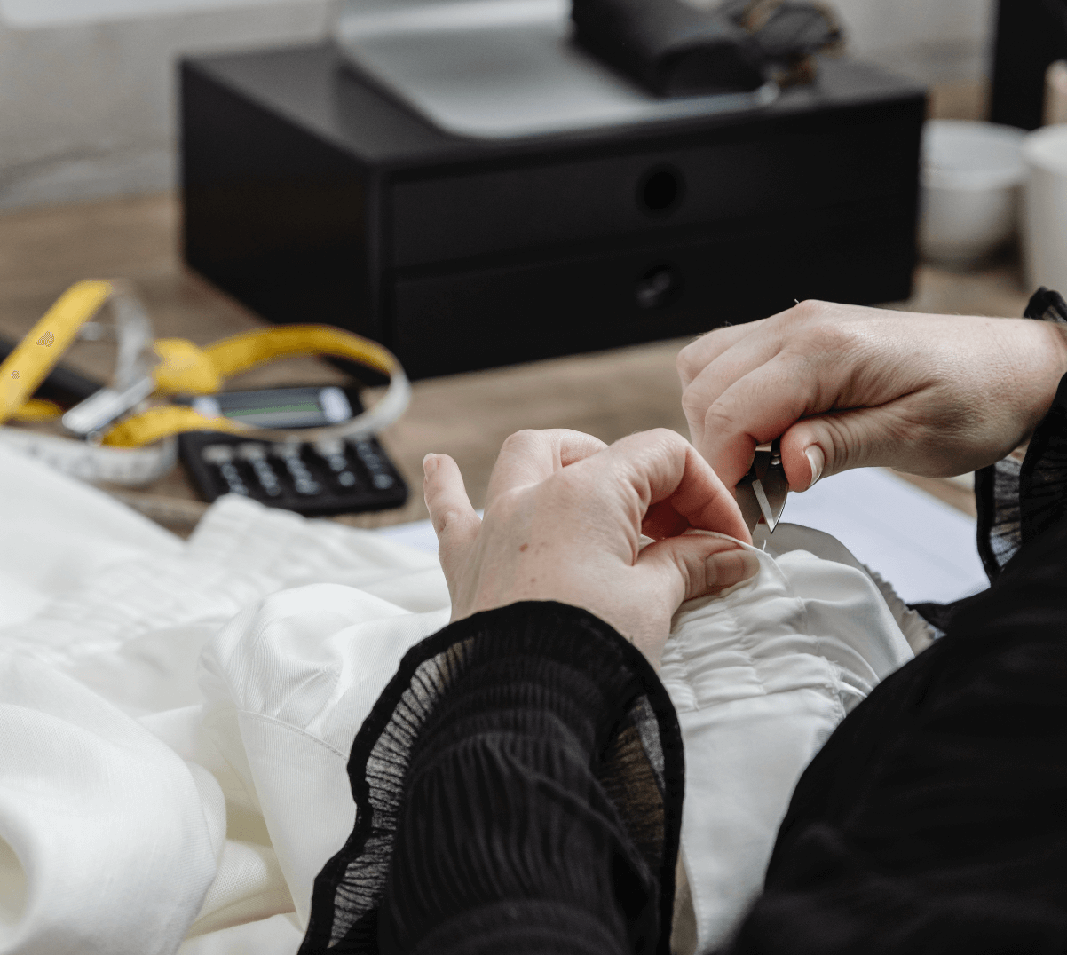 Fashion Designer clipping loose threads off a sample garment for quality control (QC).