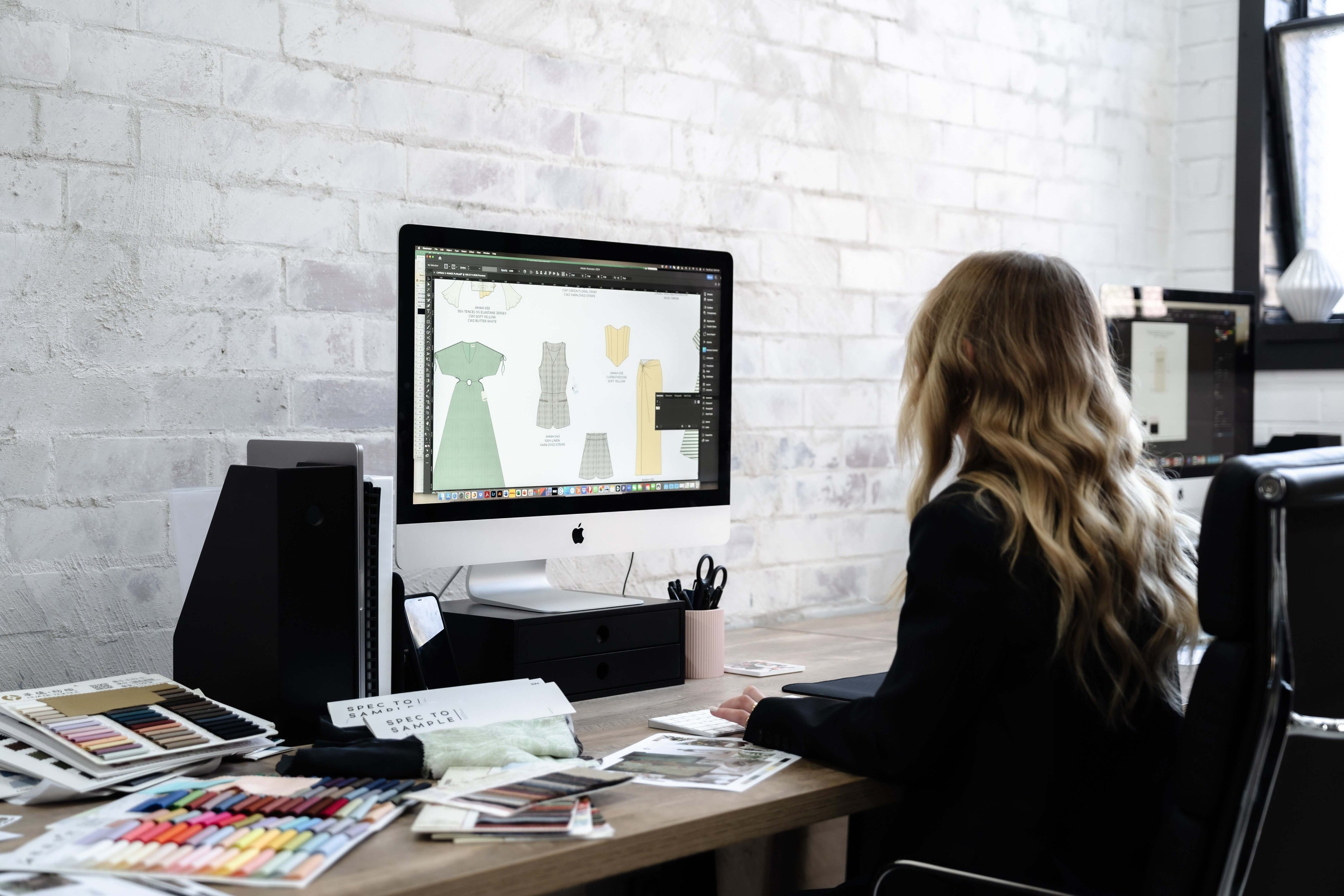 Fashion Design team reviewing purchase orders and tech packs on a computer.