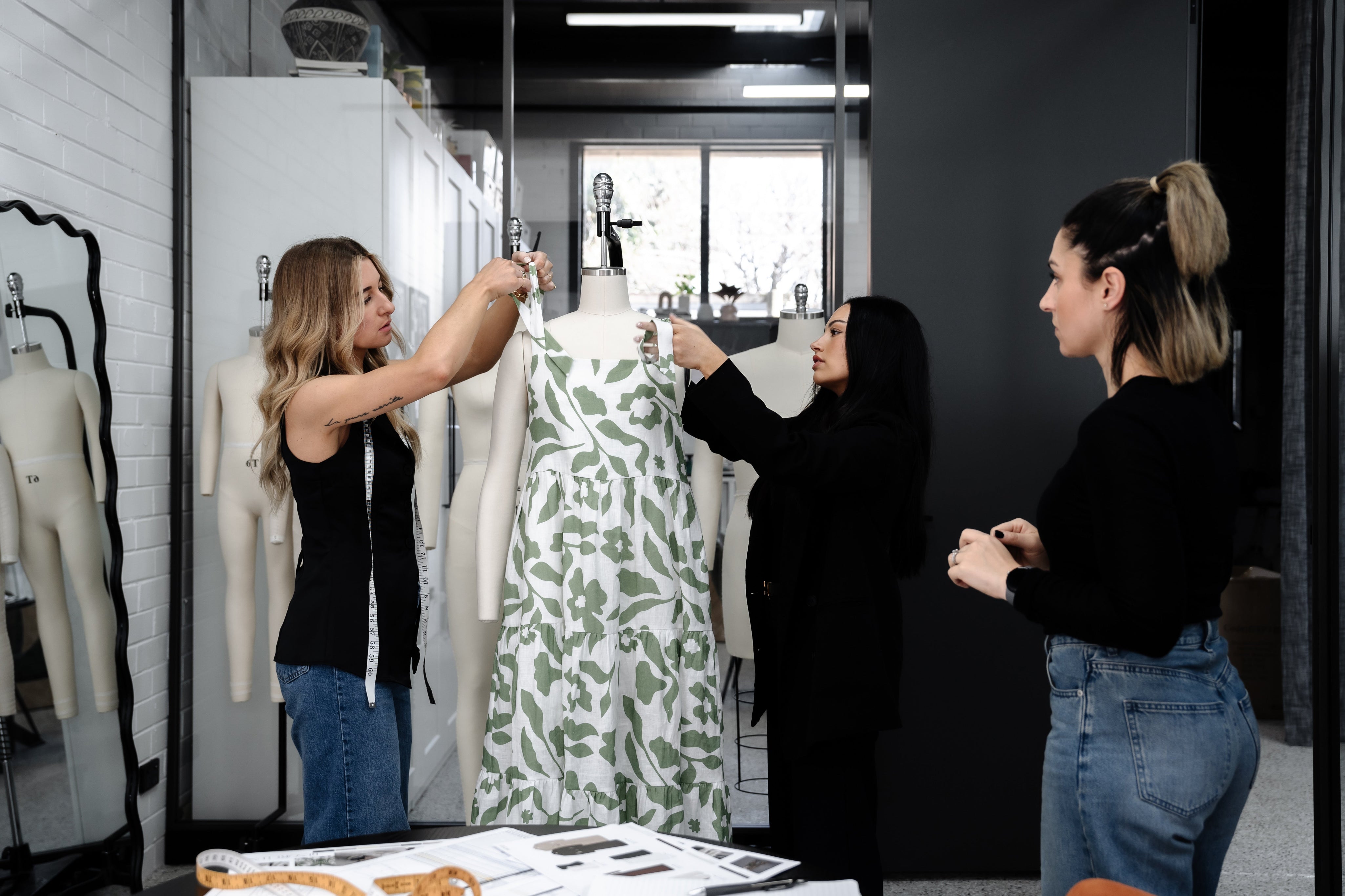 Small fashion team working together in studio, planning production tasks with a dress form.