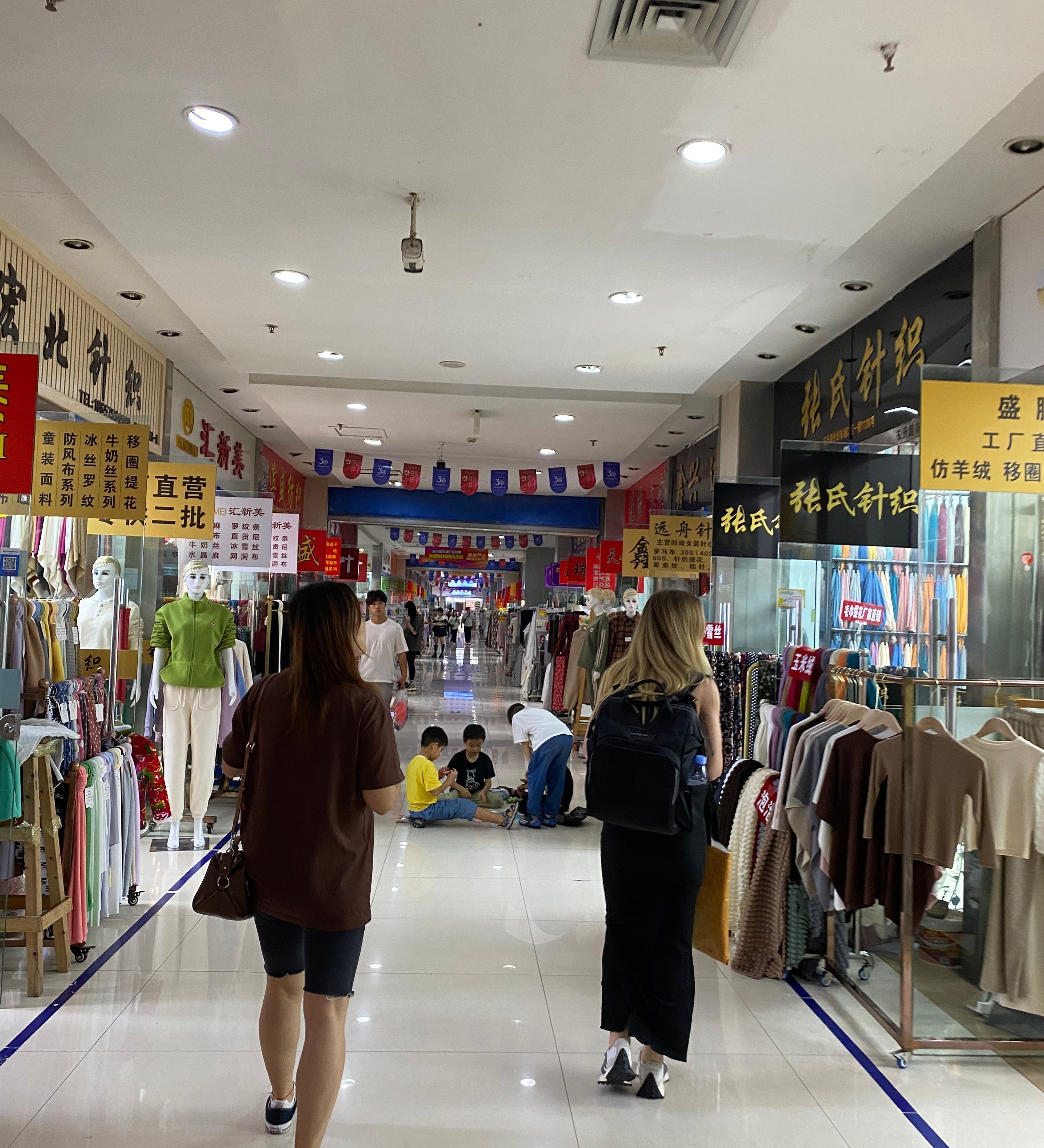 Two women shopping for fabric inside a mall in China.