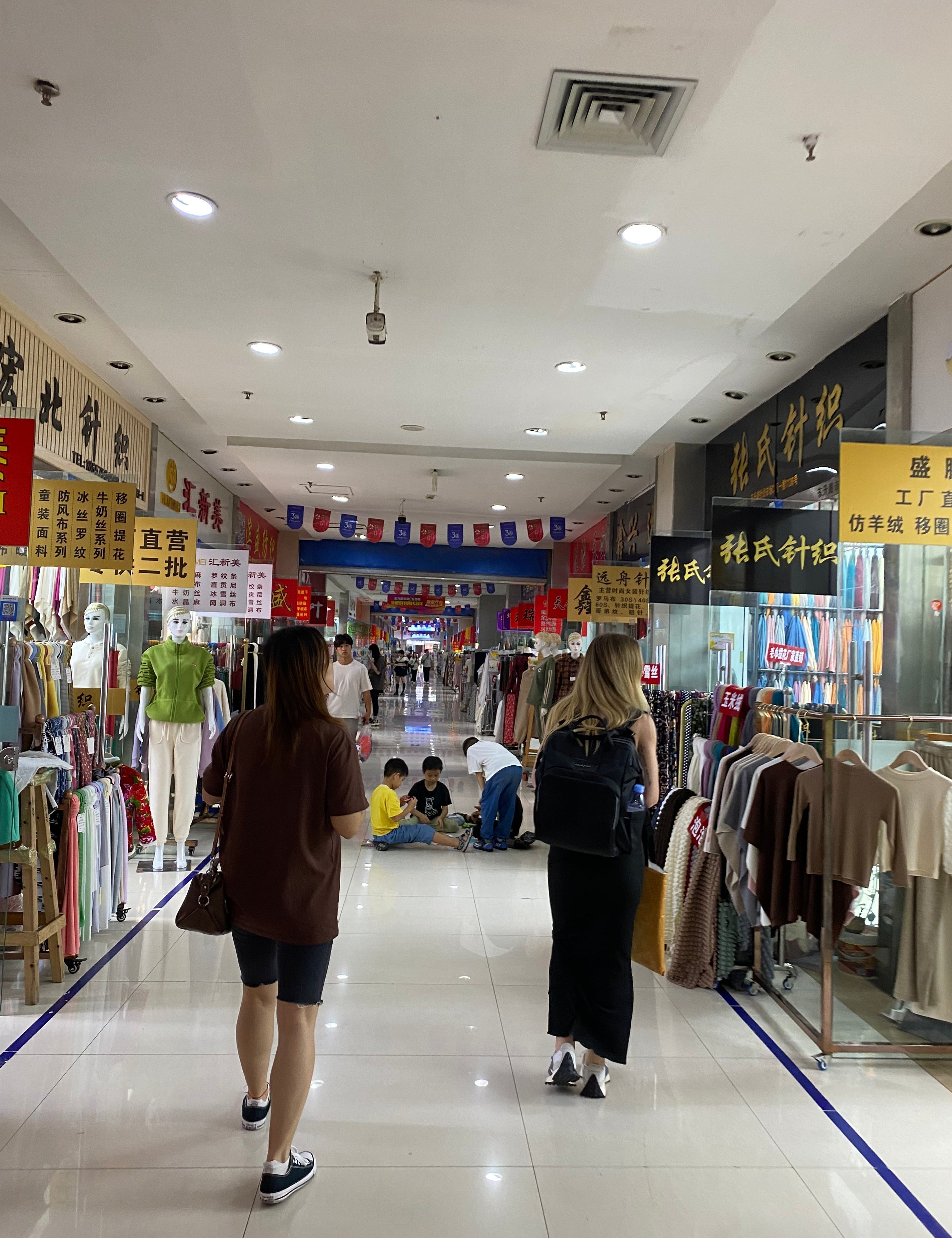 Two women shopping for fabric inside a mall in China.