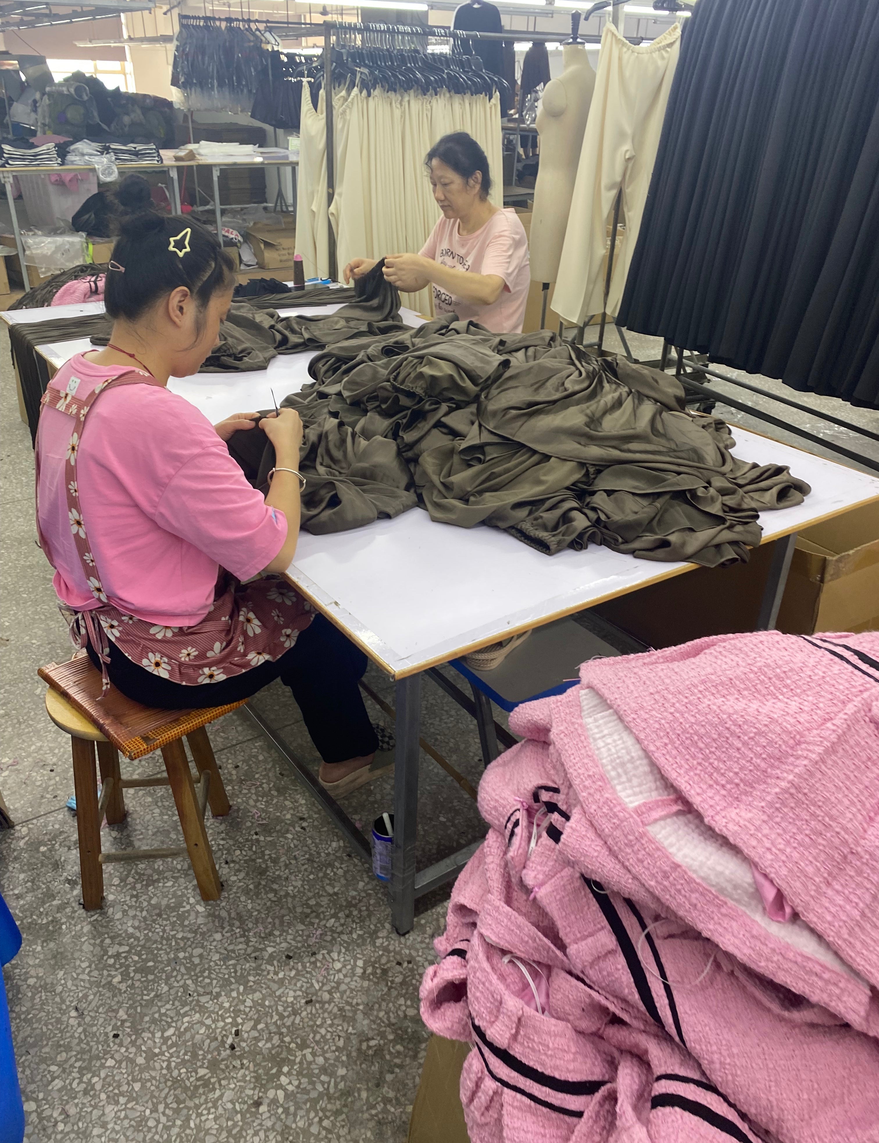 Two garment factory workers sewing clothes that were ordered at minimum order quantity.