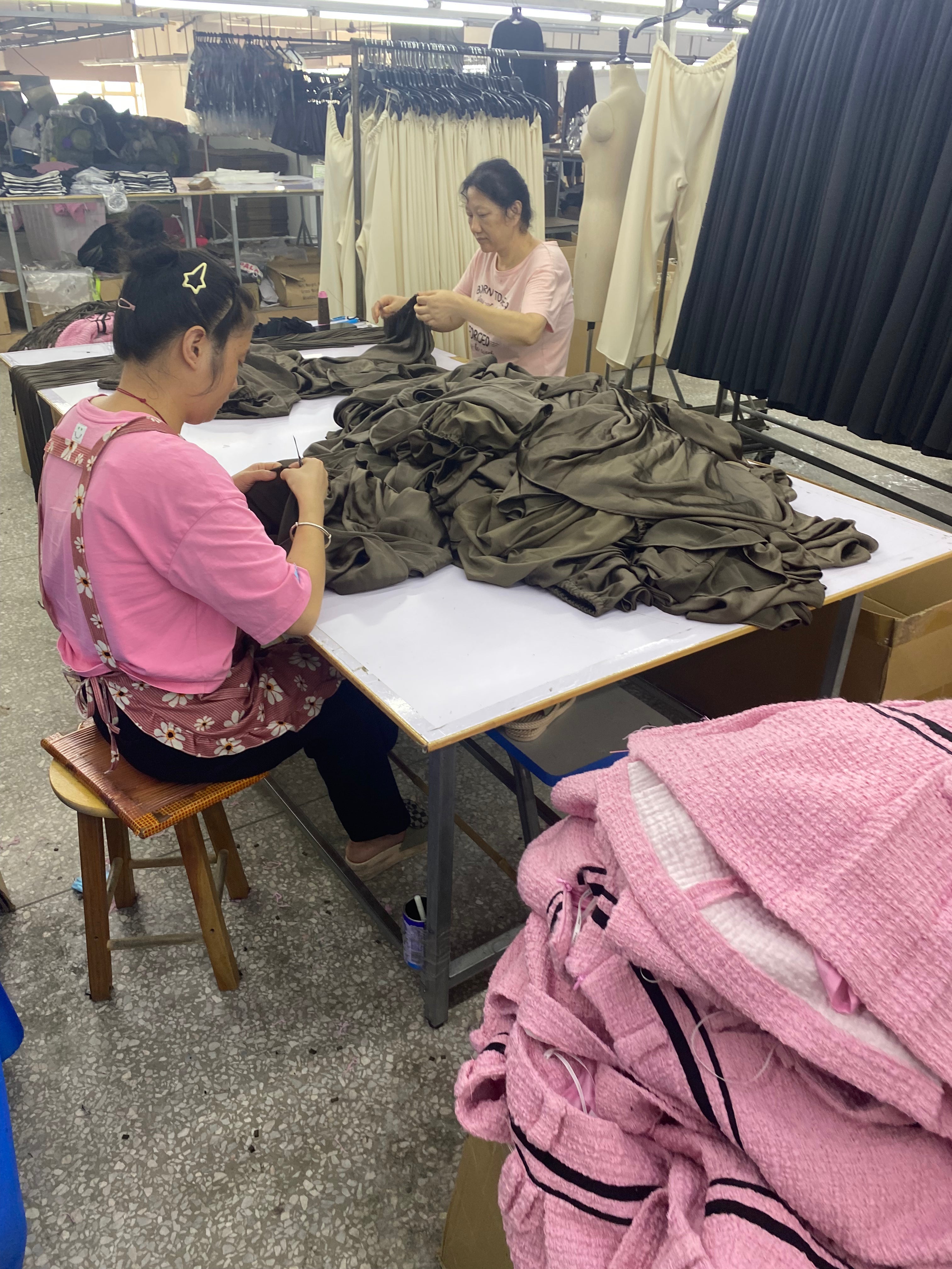 Two garment factory workers sewing clothes that were ordered at minimum order quantity.