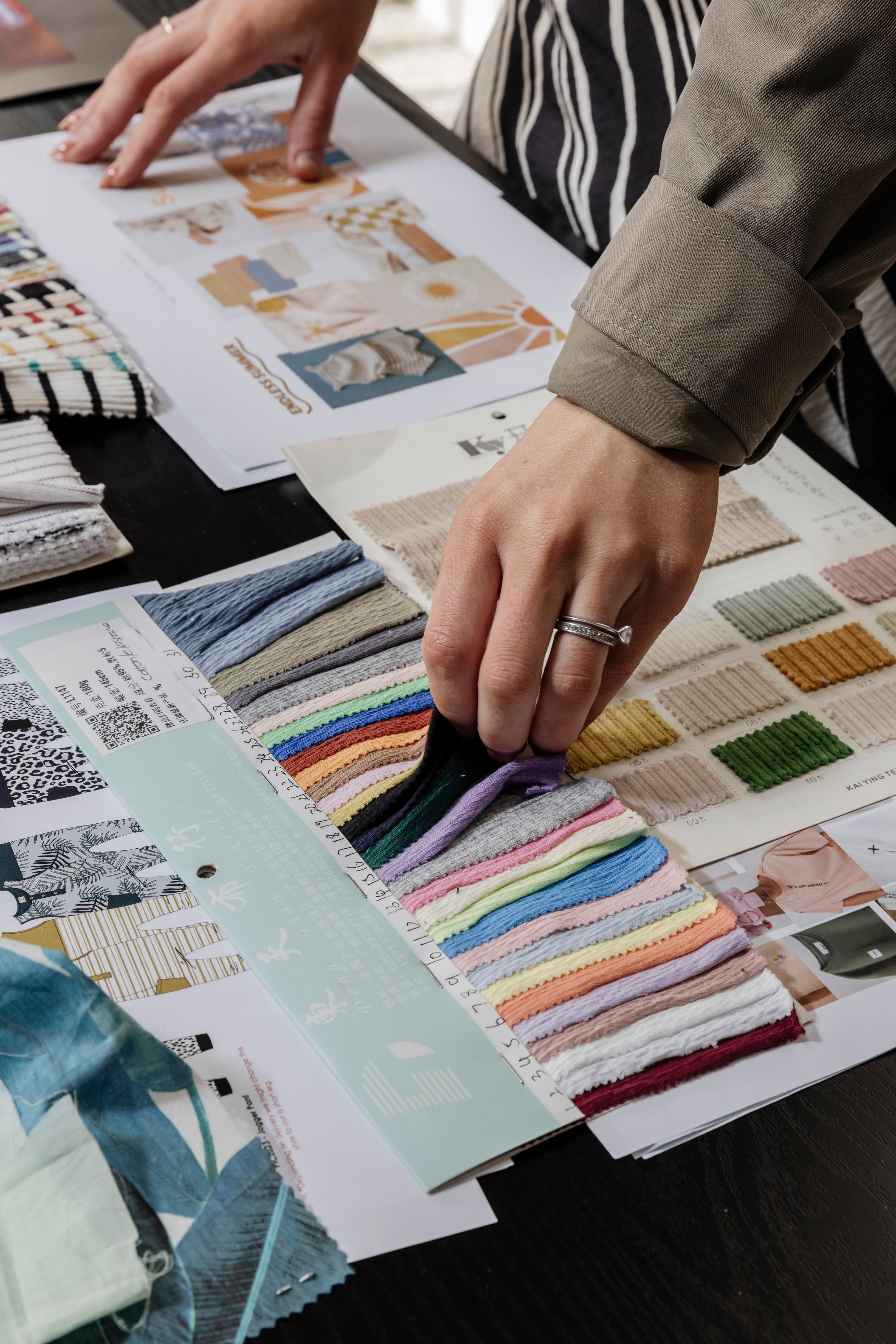 The hands of a lady choosing the right fabric for her fashion brand from fabric swatches.